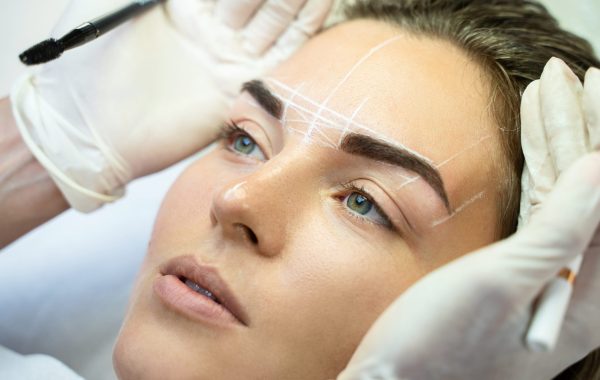 Young woman during professional eyebrow mapping procedure
